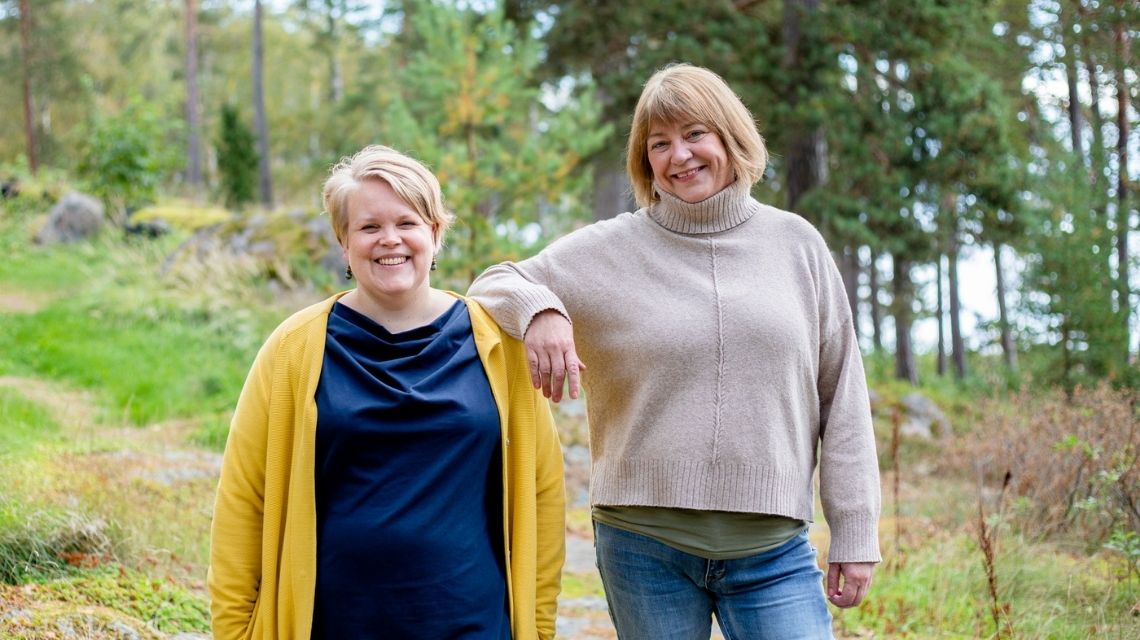 Jutta Lithovius ja Tiina Flygare nauravat iloisesti metsässä.