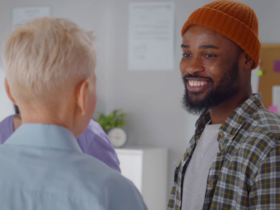 Kolme henkilöä seisoo toimistotilassa keskustelemassa.