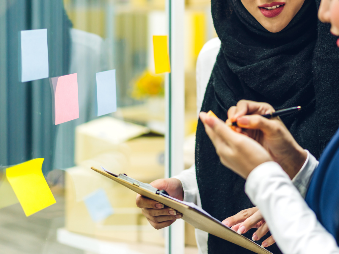 Kaksi henkilöä suunnittelee post it -lappujen avulla.