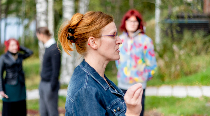 Krissu Sirola-Korhonen puhuu ryhmälle ulkona vehreässä maisemassa loppukesällä.