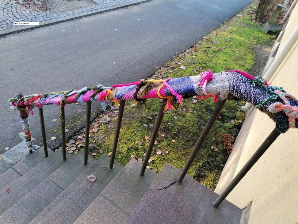 Portaiden kaiteeseen on kiinnitetty värikäs neulekudelma.