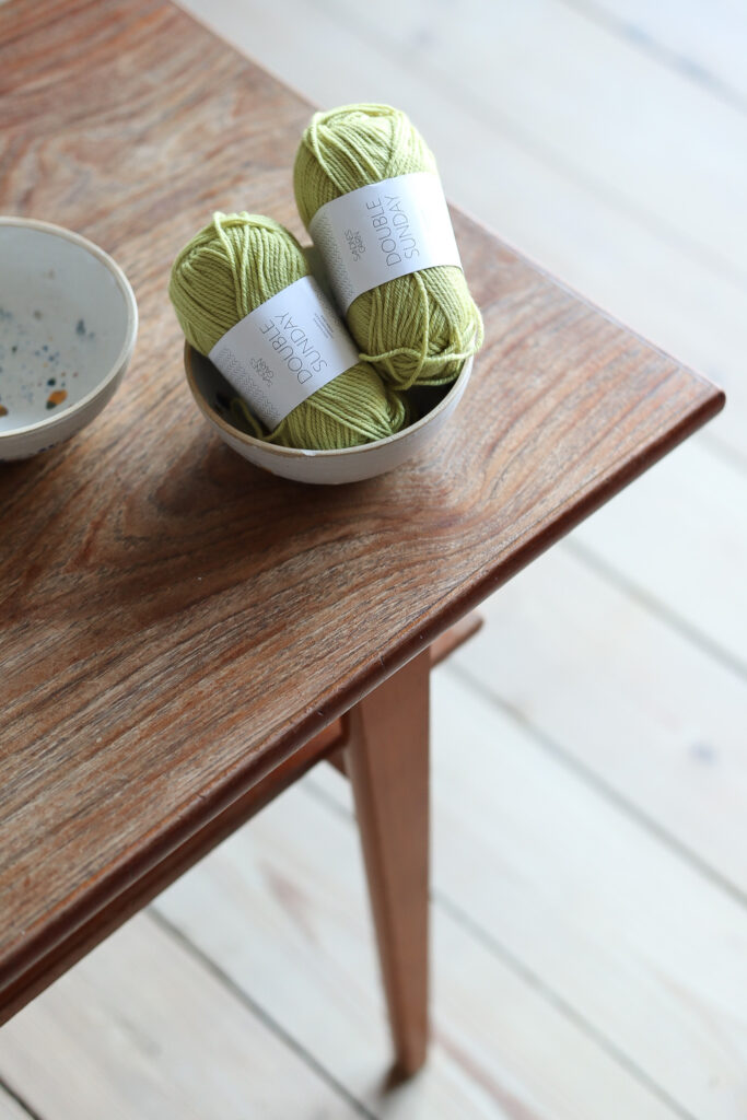 Kaksi lankakerää keraamisessa kulhossa sohvapöydällä.