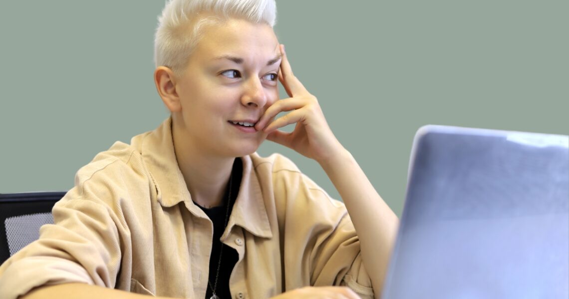 Henkilö istuu kannettavan tietokoneen ääressä pohtimassa käteensä nojaten.