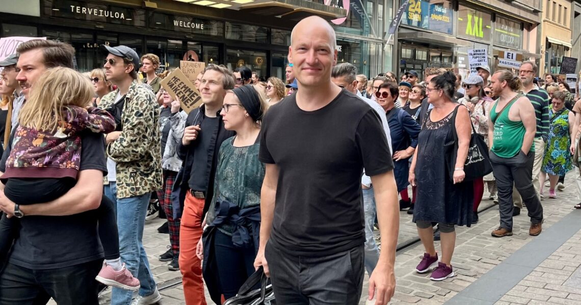 Pelle Dragsted kävelee mielenosoittajien kulkueessa Helsingissä Aleksanterinkadulla. Yhdellä mielenosoittajalla on kyltti, jossa lukee: Me emme vaikene. Toisessa kyltissä lukee: Ei rasismille.