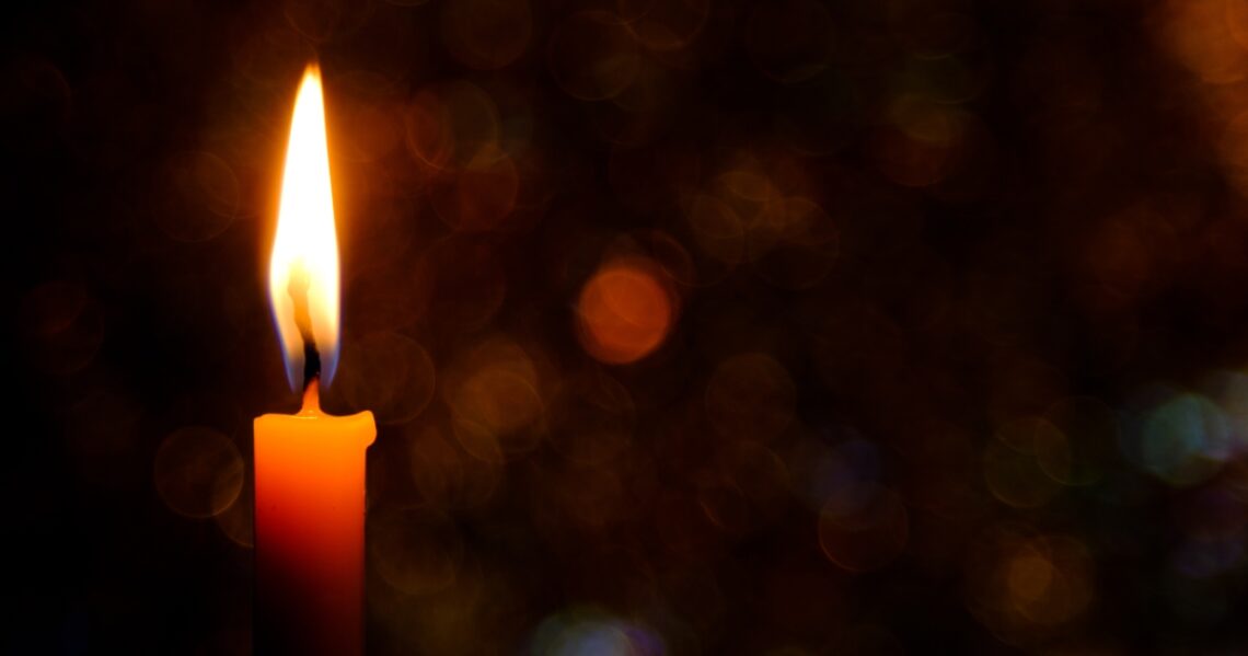 Kynttilän liekki pimeässä.