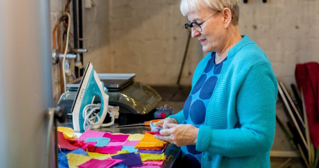 Henkilö on käsityöluokassa ja katselee pöydällä olevia värikkäitä kangastilkkuja.